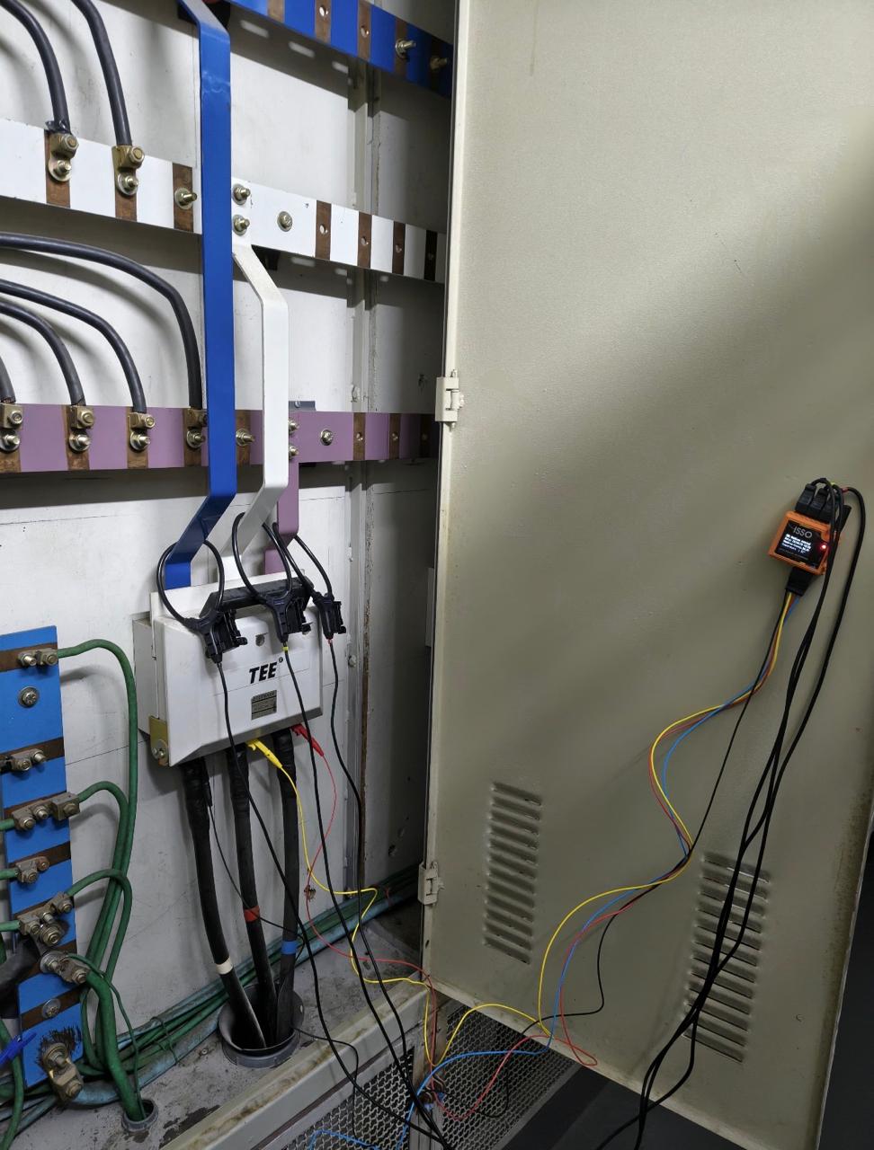 Analisador de qualidade de energia instalado na porta de um painel elétrico, com cabos de medição conectados à instalação.